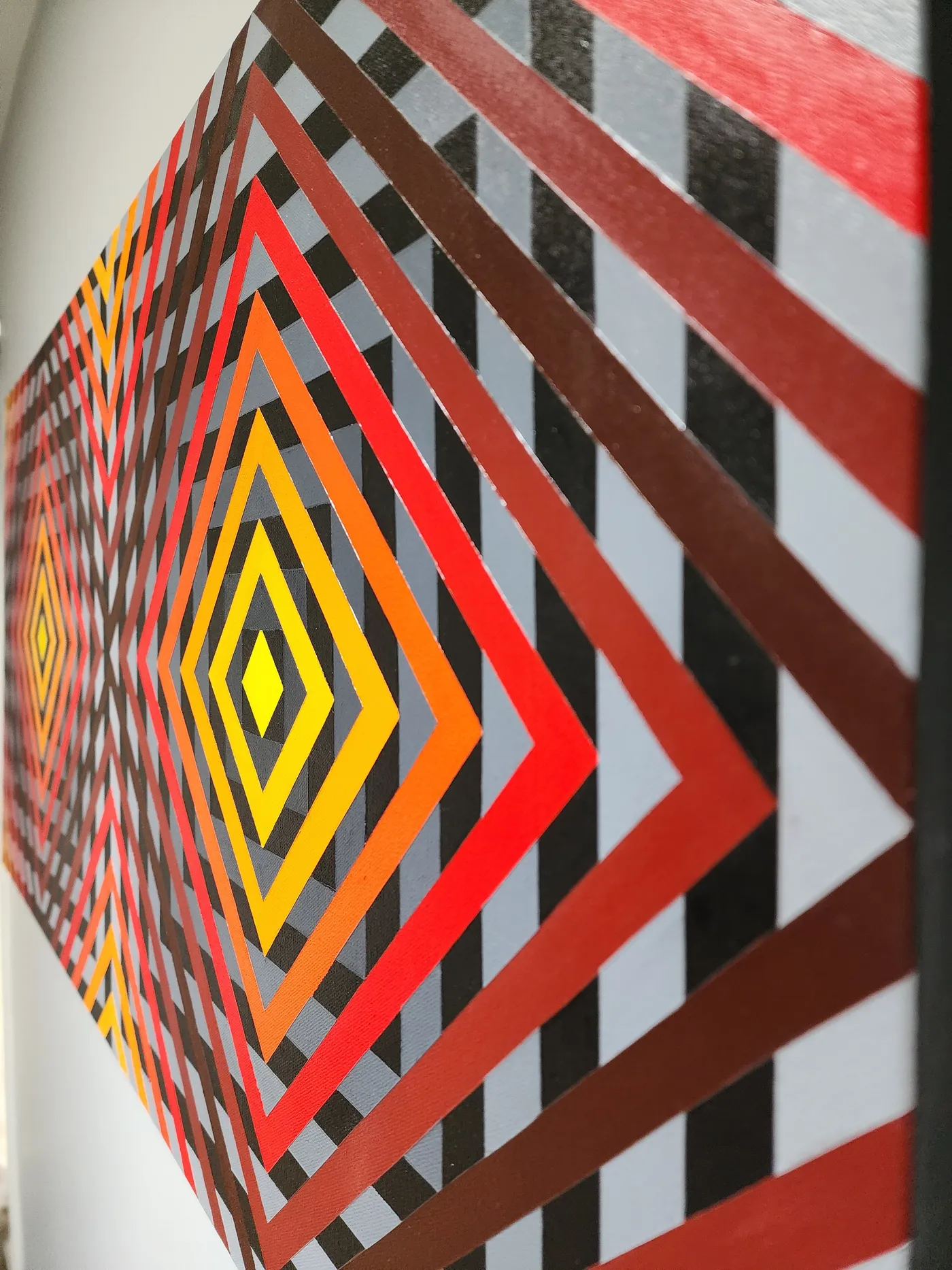 Angled view of the piece with its bright, red and orange alternating pattern.