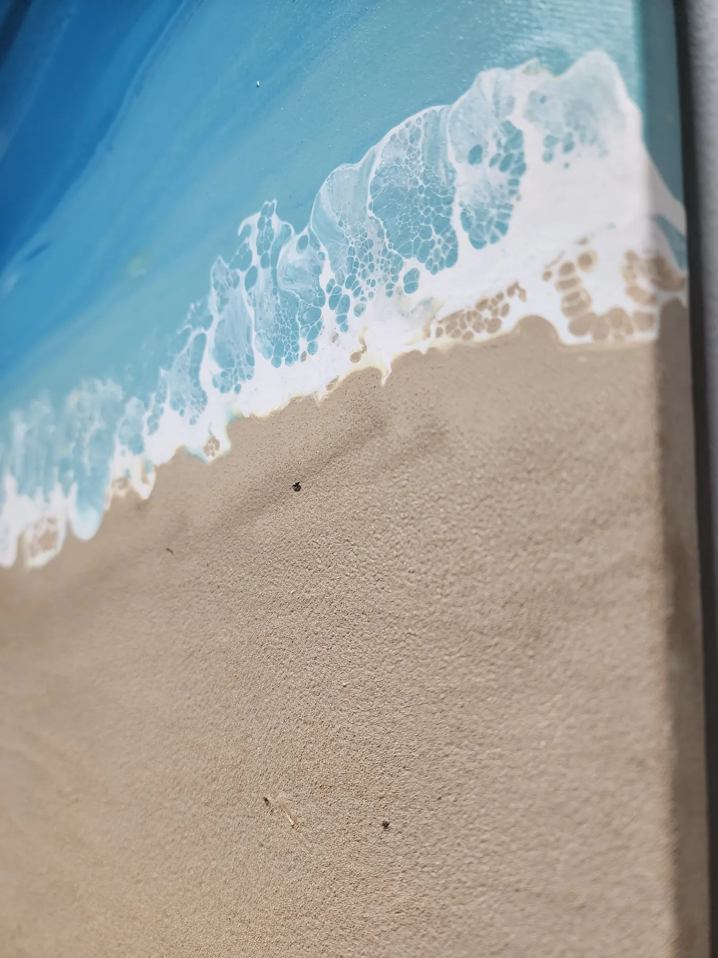 A close up shot of the piece showing the beach and fluid art ocean wrapping the sides of the canvas.