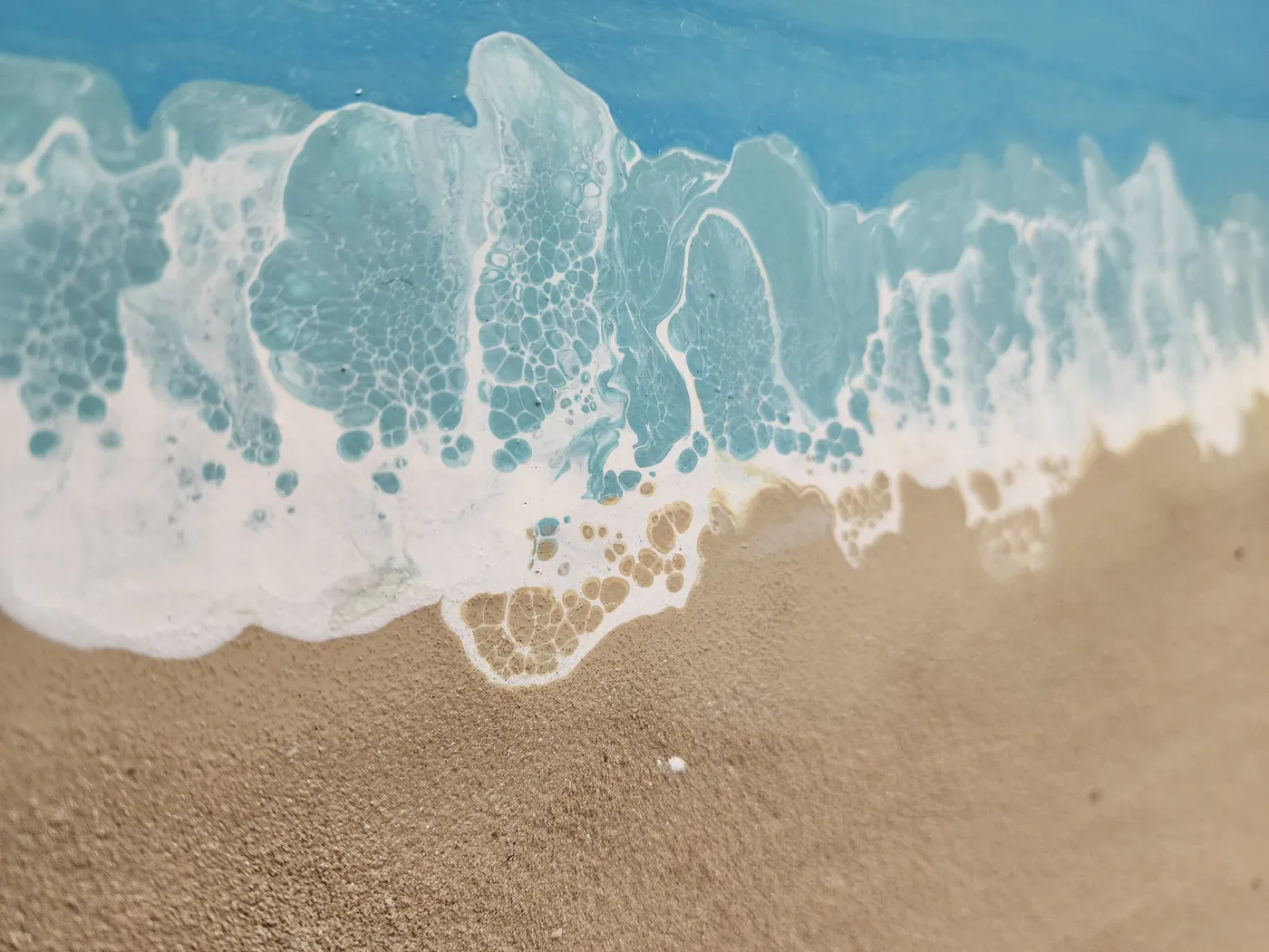 An up-close view of the fluid art crashing waves at the beach.