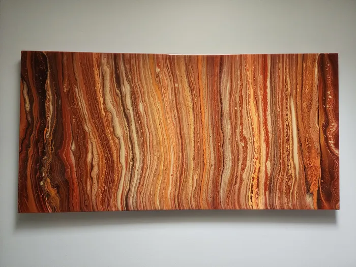 A large canvas painting mounted to a neutral wall. The painting is a fluid art piece in stunning reds, oranges, and tans, giving the look of the planet Jupitor or Mars.