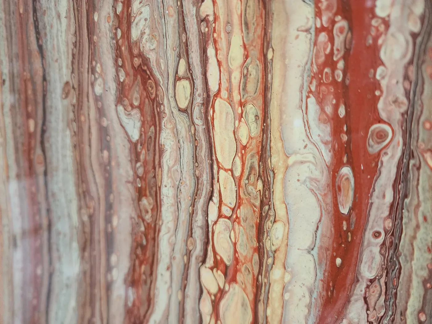 A close-up view of the detail in the fluid art showing red, orange, and tan ribbons and cells.