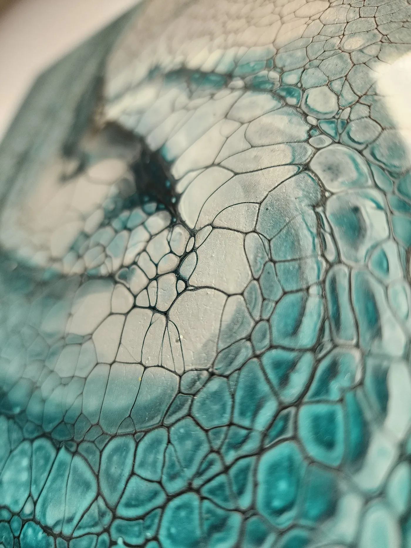An up-close view of the center of a the fluid art piece with swirling turquoise, grays, and whites showing the metallic flecks.