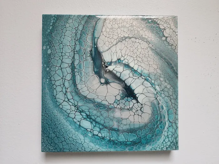 A small, square art piece on a neutral wall. The piece is fluid art with turquoise, gray, and white swirling into the center.