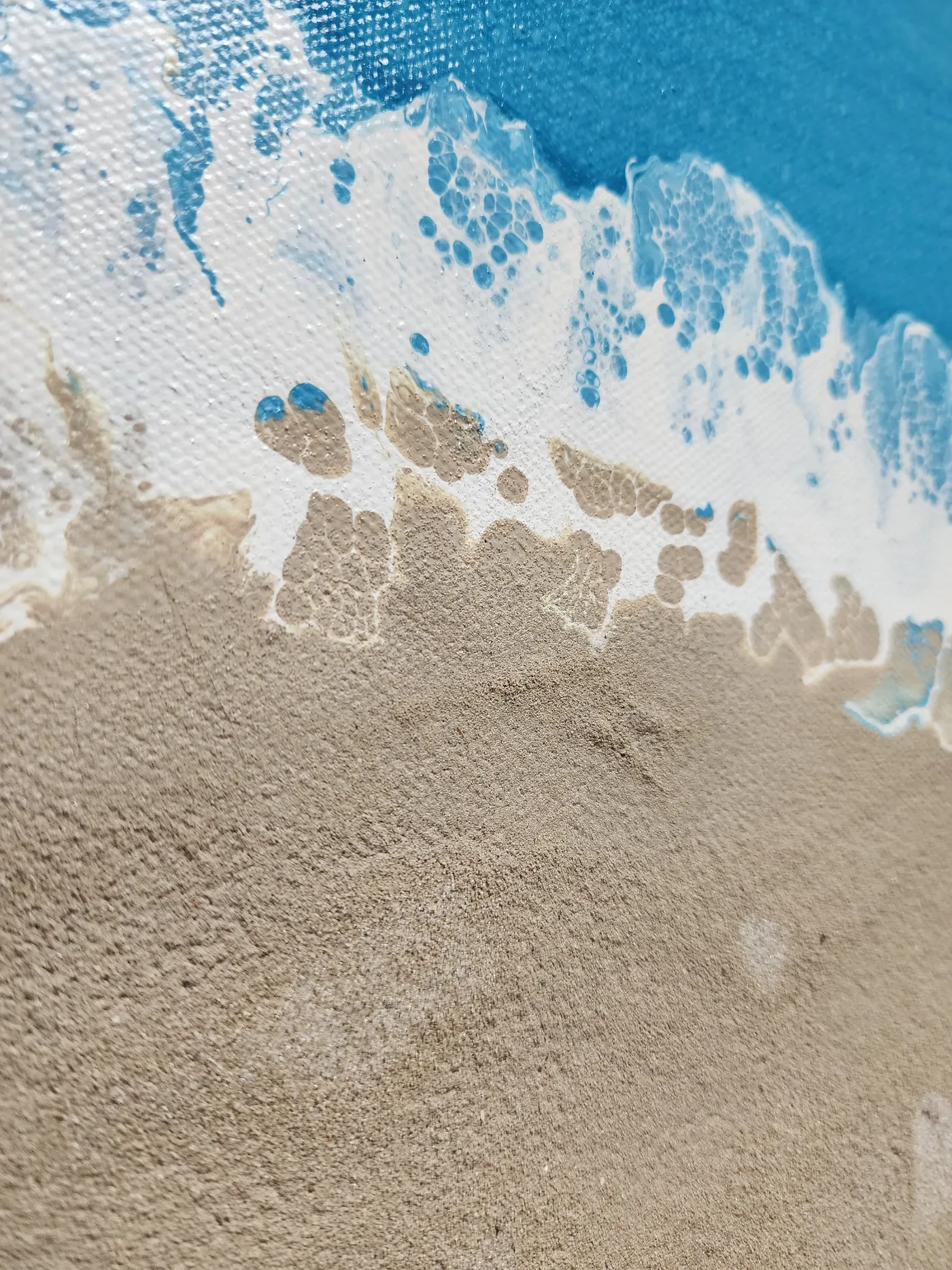 An up-close shot of the seascape art piece showing where the ocean and real art meet, highlighting the sand's texture and the foam detail.