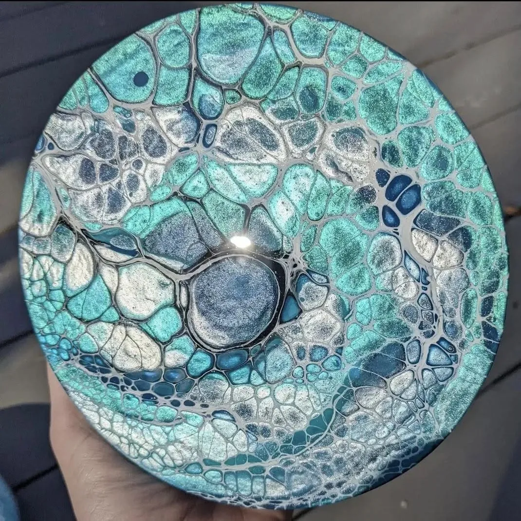Round canvas poured in blue and silver, with one large dark cell just below centre.