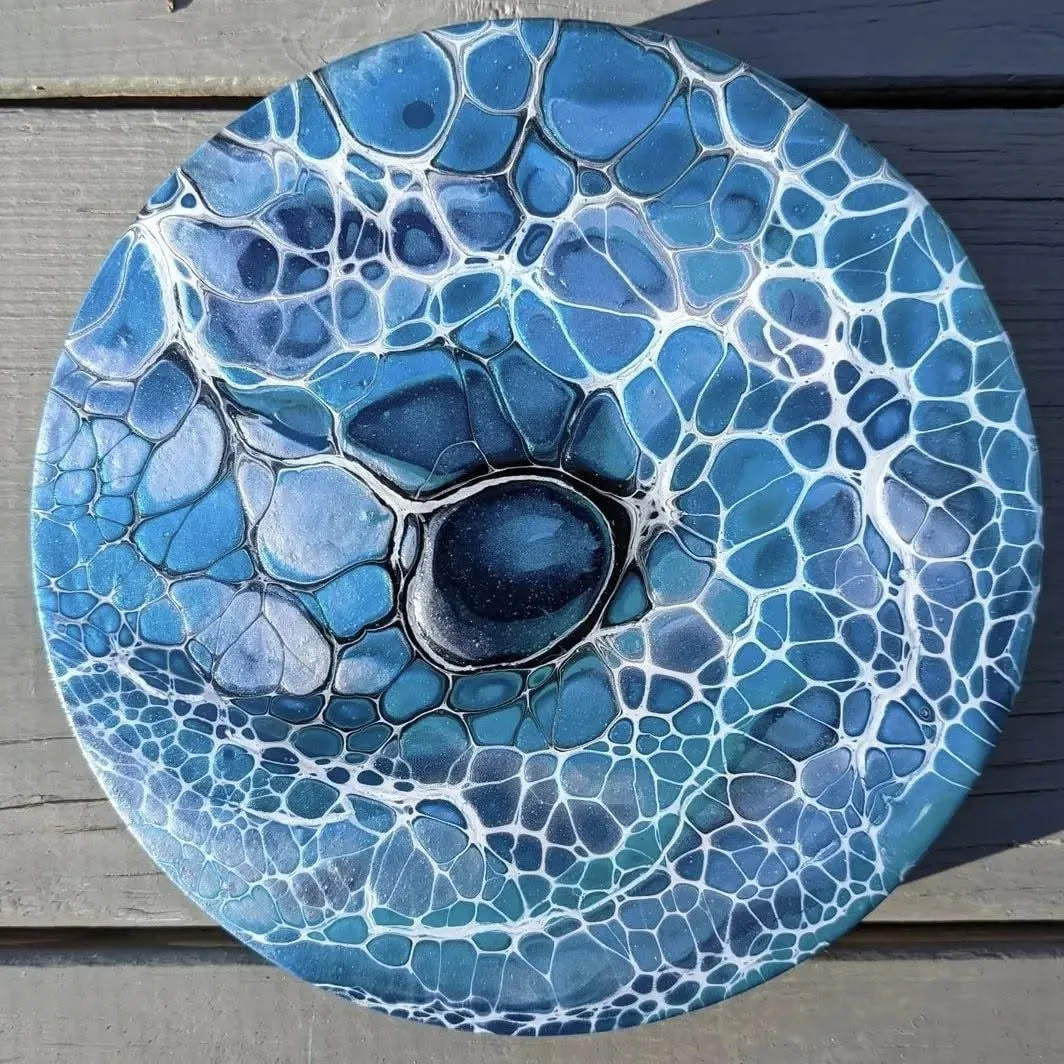 Overhead view of the round pour resting on grey decking, cells graduating from pale blue to deep navy.