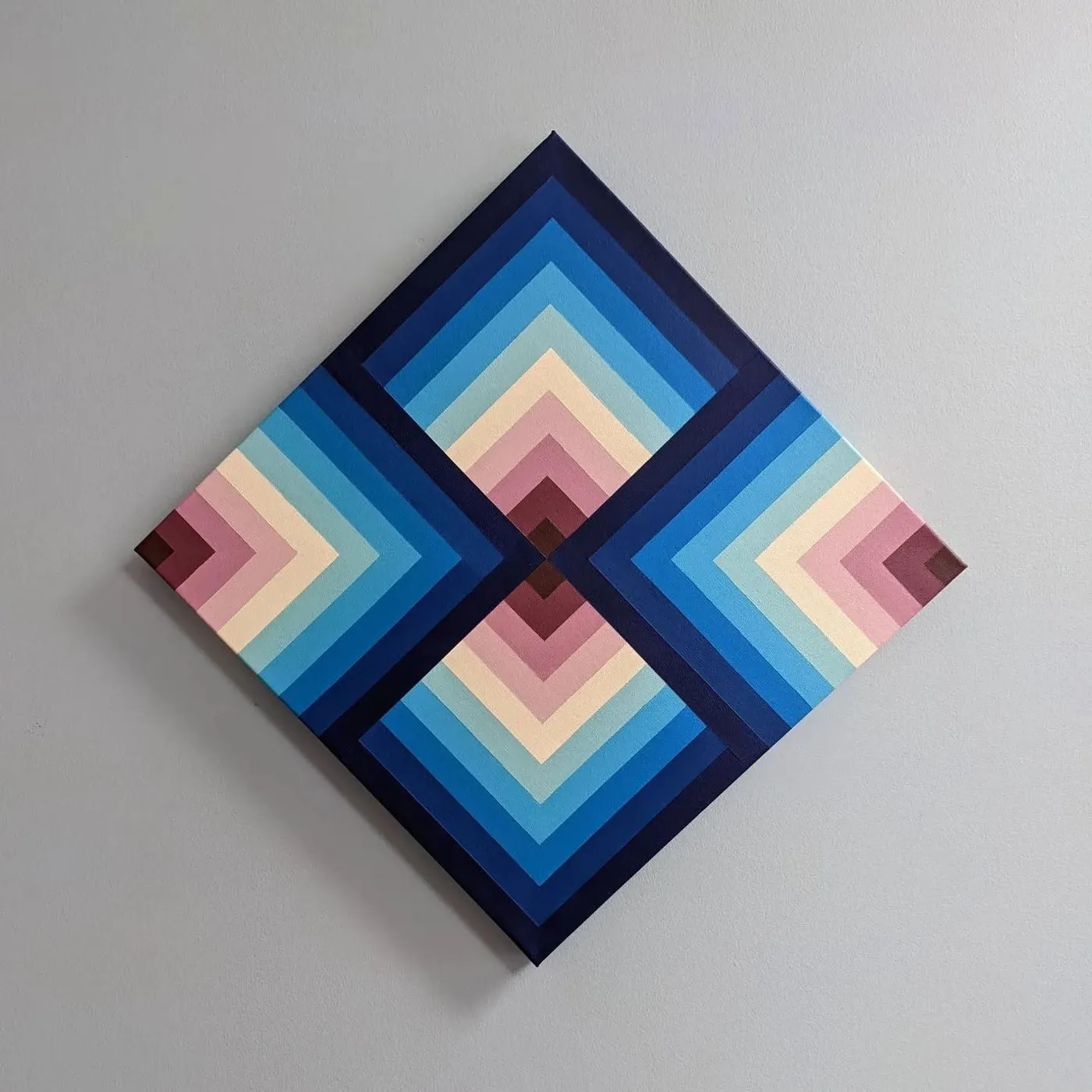 Square canvas hung as a diamond, painted with four sets of nested chevrons in navy, blue, cream and rose radiating from the centre.